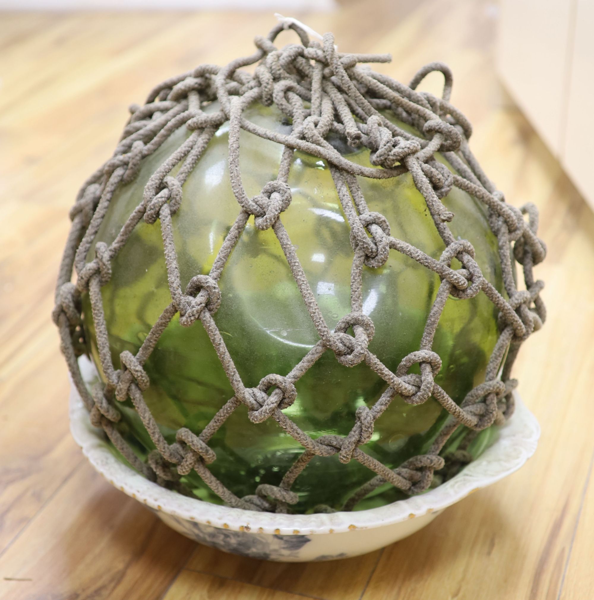 A large glass buoy with netting and a Staffordshire pottery basin